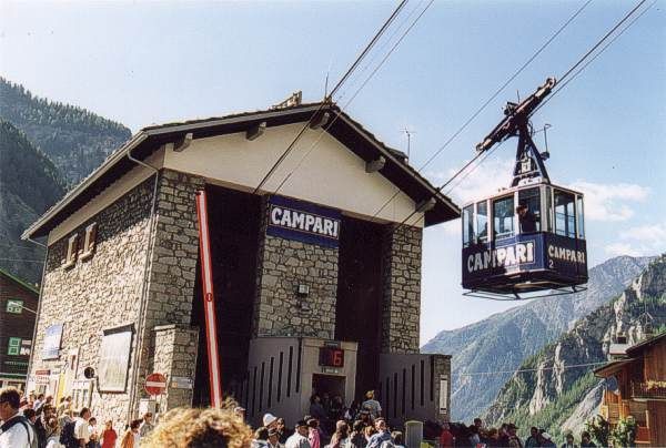 Aspettando il proprio turno per salire sul primo tratto della funivia, si osservano le cabine salire e scendere dall'affollatissimo piazzale.