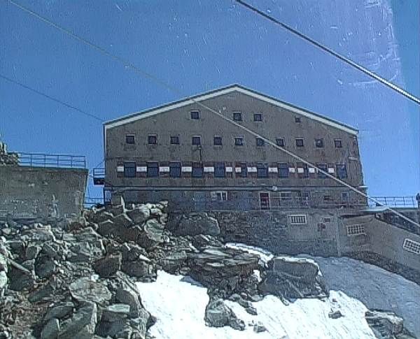 Poco dopo la partenza dalla stazione del Rifugio Torino Vecchio, diretti verso la punta Helbronner. Alla nostra destra sfila l'edificio del Rifugio Torino Nuovo. A destra della foto parte la scala coperta che porta al Vecchio.