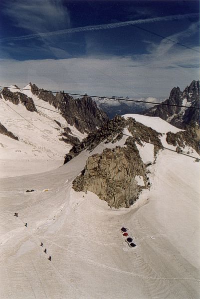 Appena prima del pilone sospeso (si vedono chiaramente i tre robusti cavi che lo tengono in posizione) si vedono meglio le cordate che si dirigono in direzione dell'Aiguille du Midi e il gruppo di tende.