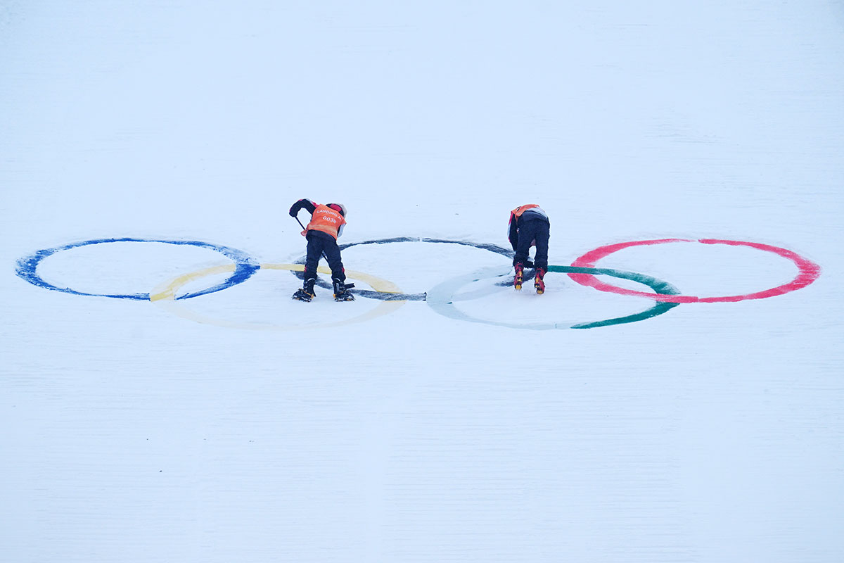  Track officials clear snow from the olympic rings during a Ski Jumping Beijing