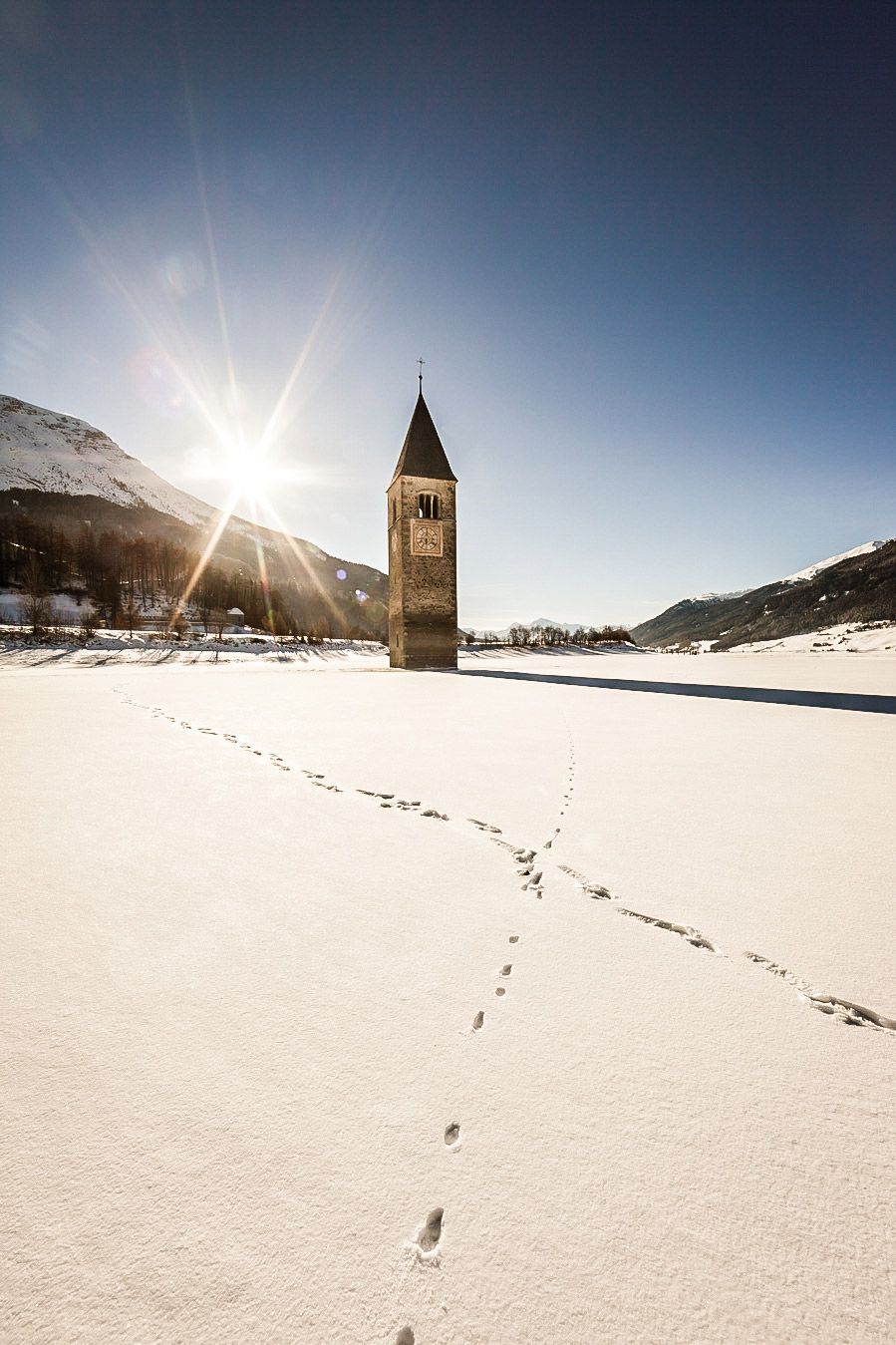 vecchio campanile di Curon che emerge dalle acque del lago di Resia ghiacciato