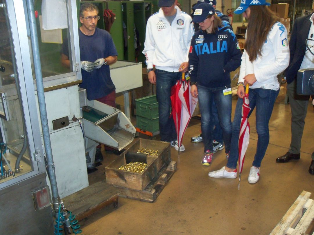 Dopo la visita all'armeria, il passaggio alla linea produttiva delle cartucce calibro 22. Dominik Windisch, Karin Oberhofer e Lisa Vittozzi osservano i proiettili appena prodotti che sparareranno durante l'inverno.